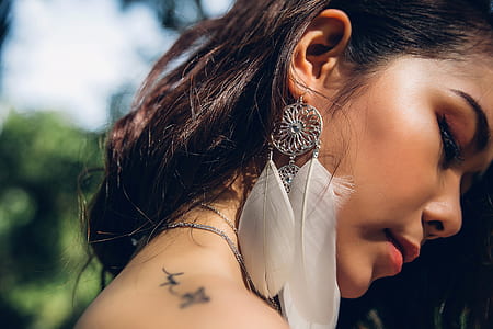 close up photography of woman wearing feather-themed earring thumbnail