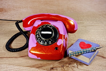 red and pink rotary phone beside purple and red heart printed book and pen thumbnail