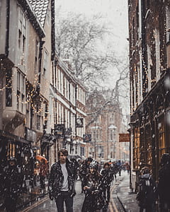 man and woman walking in the street near buildings under snow thumbnail