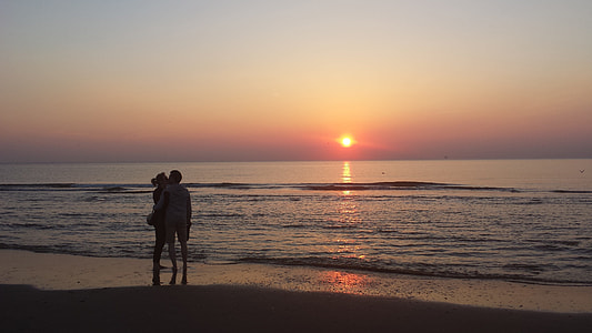 silhouette of man and woman kissing on shoreline during golden hour thumbnail