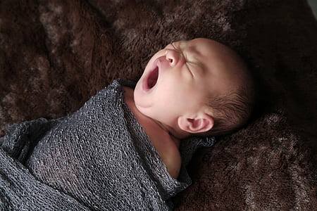 yawning baby wrapped with gray cloth thumbnail