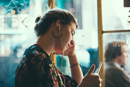 selective focus photography of woman in black and multicolored floral top with white earbuds thumbnail