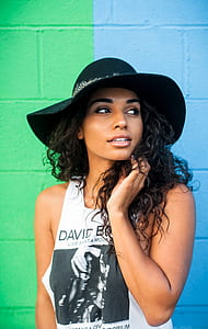 woman standing beside wall while holder her hair during daytime thumbnail