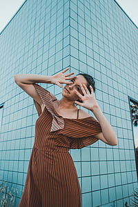 woman raising her hands near concrete building at daytime thumbnail