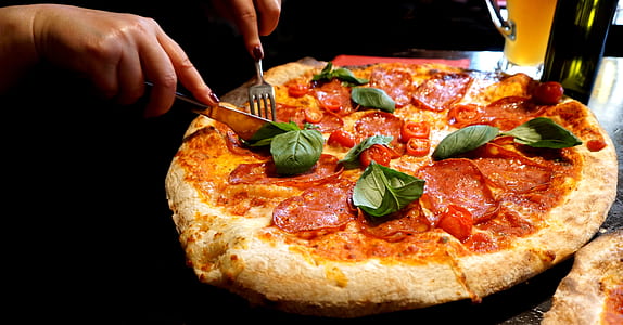 person slicing pepperoni pizza thumbnail