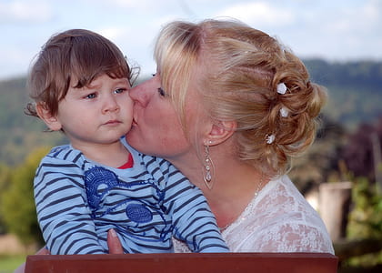 woman kissing boy in blue striped shirt thumbnail