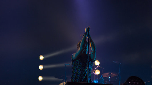 man holding microphone stand behind drum set thumbnail
