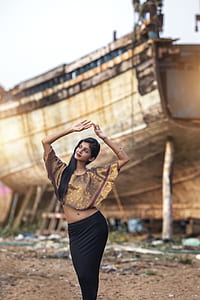 woman in brown floral crop top raising her hands near shipwreck thumbnail