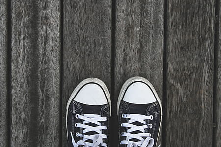 pair of black low-top sneakers on gray wooden floor thumbnail