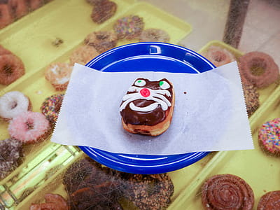 A donut with a cat face on it sitting on a blue plate. thumbnail