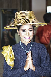smiling woman wearing black long-sleeved zip-up top and brown rattan hat thumbnail