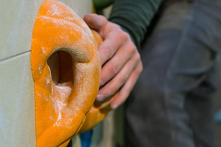 person holding on orange climbing wall thumbnail
