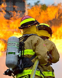 two firemen holding host near fire during daytime thumbnail