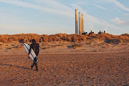 man holding surfboard walking on sand thumbnail