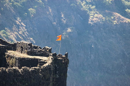orange flag standing on cliff during daytime thumbnail