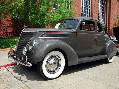 classic gray roadster coupe parked near brown building thumbnail
