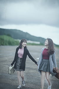 two women holding walking on road thumbnail