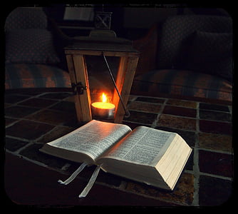 open book near candle lantern inside room thumbnail