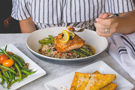 person holding gray fork in front of grilled meat on black and white bowl thumbnail