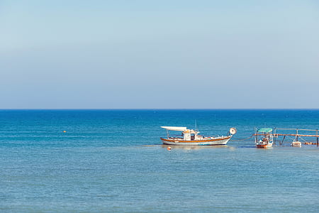 two white boats sailing on body of water under blue sky during daytime thumbnail