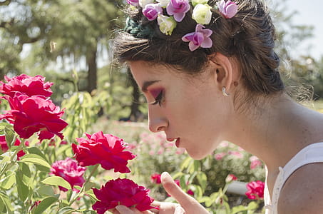Woman in Floral Headdress Sniffing on Red Flowers thumbnail