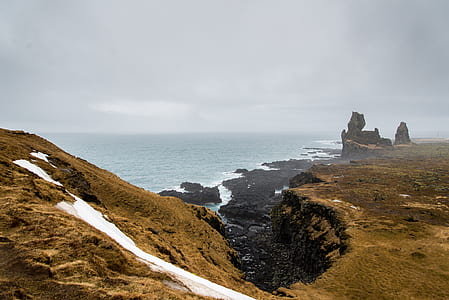 landscape photography of sea near hill thumbnail