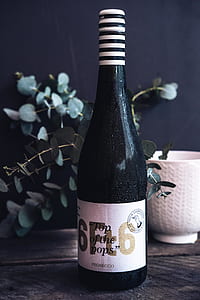 black wine bottle near vase thumbnail