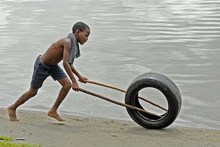 boy playing with tire at waterside thumbnail