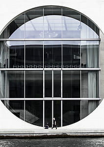two person standing and sitting in front building during daytime thumbnail