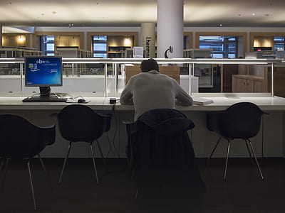 man sitting on black chair while using laptop thumbnail