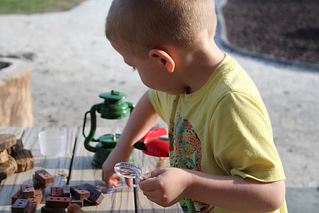 child wearing yellow shirt beside table near tubular lantern thumbnail