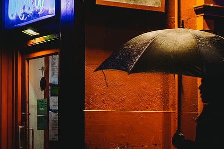 silhouette of man holding umbrella on street thumbnail