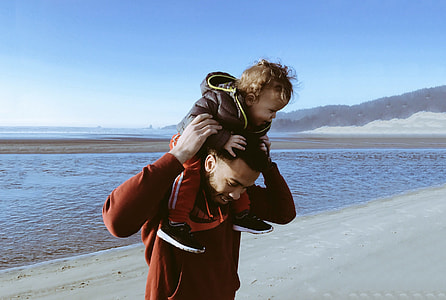 man wearing red hoodie holding child wearing black hoodie thumbnail