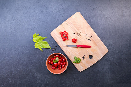 red handed knife beside slice of cherry tomatoes on chopping board thumbnail