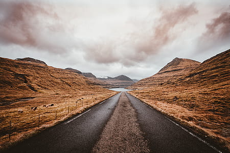 road between brown rock formation under brown sky thumbnail