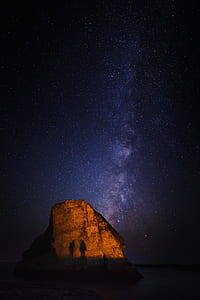 two person beside rock formation during stargazing phenomenon thumbnail