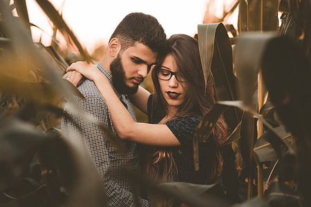man wearing gray top and woman wearing black top surrounded by green plants thumbnail