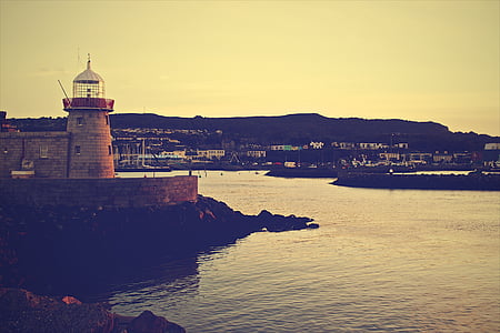 white lighthouse overlooking body of water thumbnail
