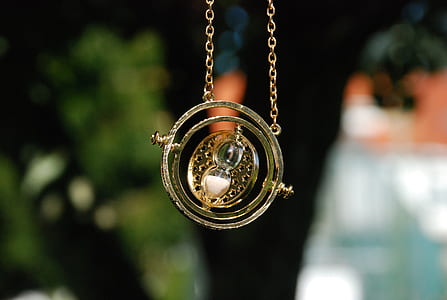 selective focus photo of gold-colored sphere hour glass pendant necklace thumbnail
