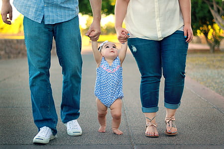 toddler between man and woman holding both hands while walking thumbnail