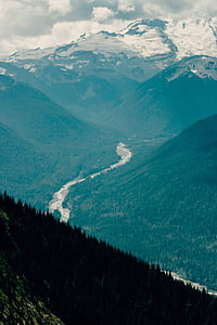 mountain terrain and river under cloudy skies thumbnail