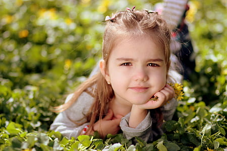 girl wearing gray crew-neck long-sleeved shirt lying on green grasses thumbnail