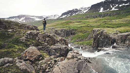 man standing on rock near of waterfalls thumbnail