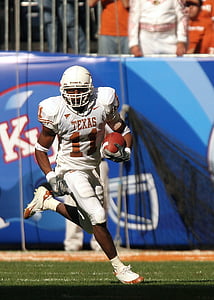 football player holding football during daytime thumbnail