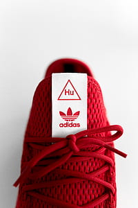 closeup photo of unpaired red adidas Tennis HU sneaker against white background thumbnail