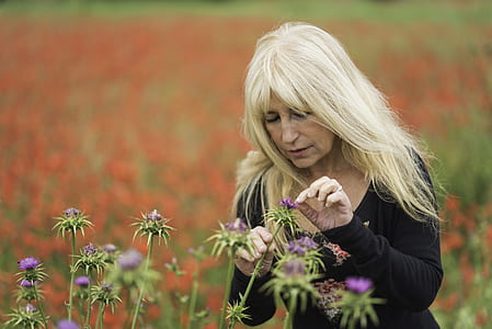 woman picking petal of purple flower during daytime thumbnail