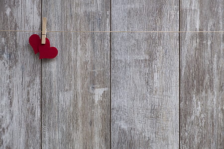 two red heart on string near grey wooden board thumbnail