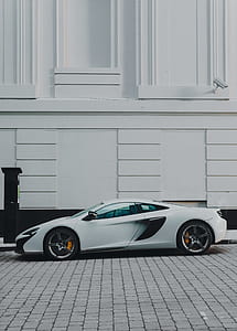 white coupe parked near white concrete building thumbnail