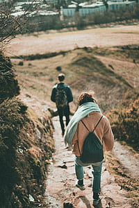 man and woman walking on dirt road during daytime thumbnail