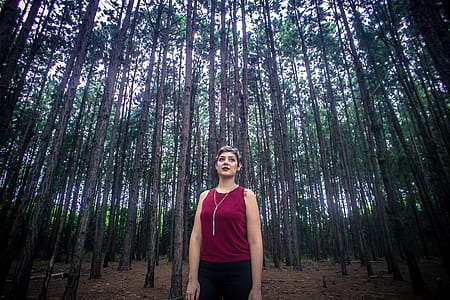 Woman Wearing Maroon Tank Top and Black Bottoms Surrounded With Brown Trees thumbnail